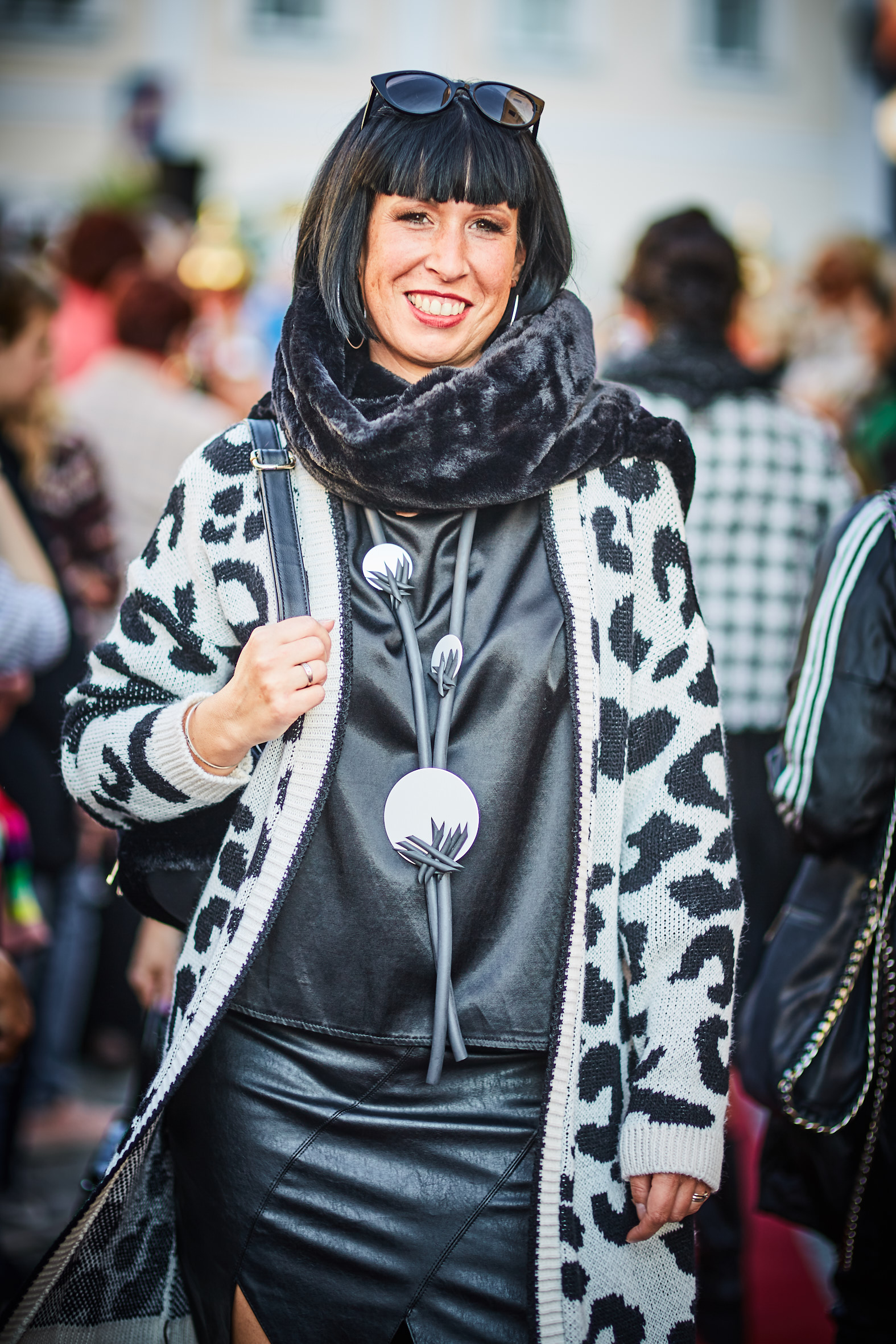 Eine sehr modern gekleidete Frau in schwarz/weis gemusterter Jacke.