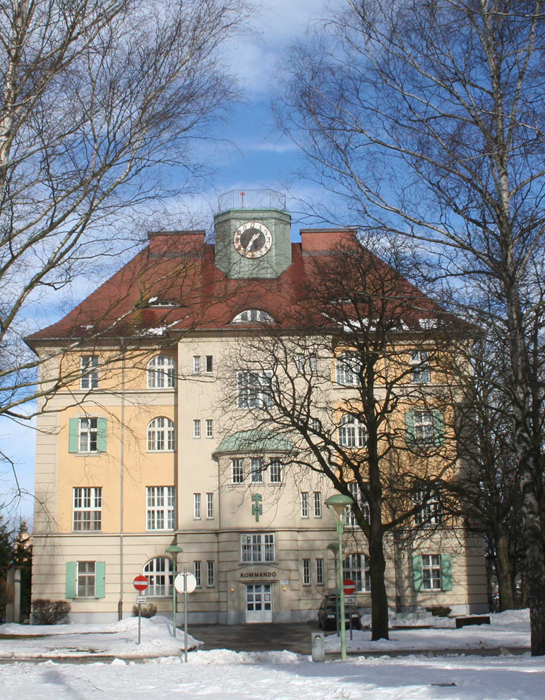 Ein Foto des gelben Kasernengebäudes mit grünem Uhrturm.