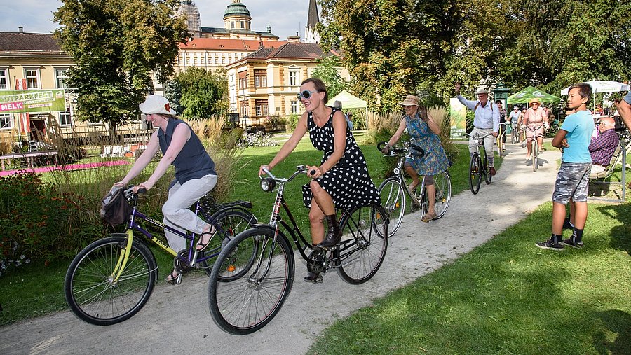 Personen die durch den Stadtpark radeln.