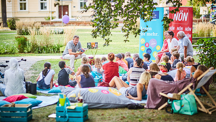 Ein Foto von Menschen, die in der Wiese sitzen und lesen.